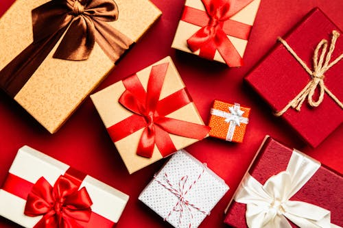 Holiday gift boxes with red and white ribbons arranged on a red background