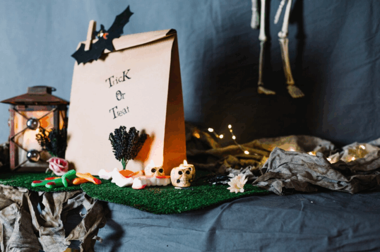 DIY Halloween trick-or-treat setup with paper bag, candy, skull decor, and spooky lantern on a festive tabletop display.