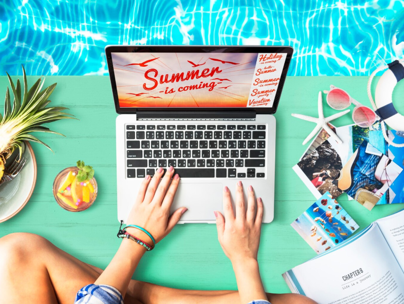 Person searching for last-minute vacation deals on a laptop by the pool with travel guides, tropical drink, and summer planning visuals.