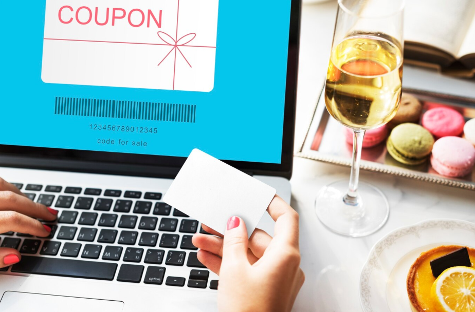Person using laptop to search for the best coupon sites for everyday items, with credit card in hand and digital promo code on screen.
